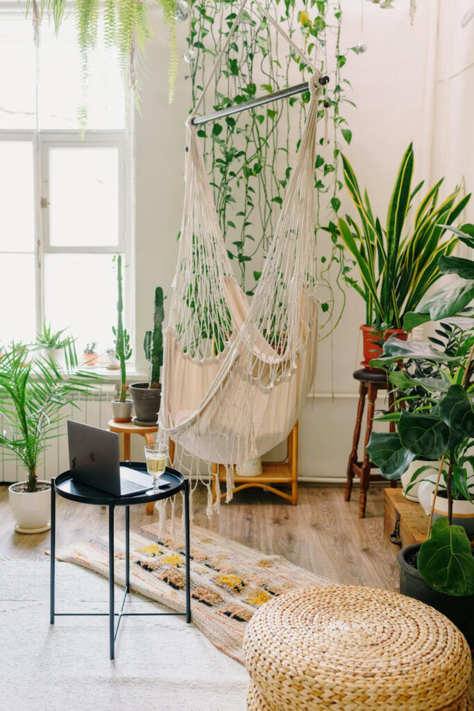 Ambiente interno com cadeira suspensa, plantas e luz natural.