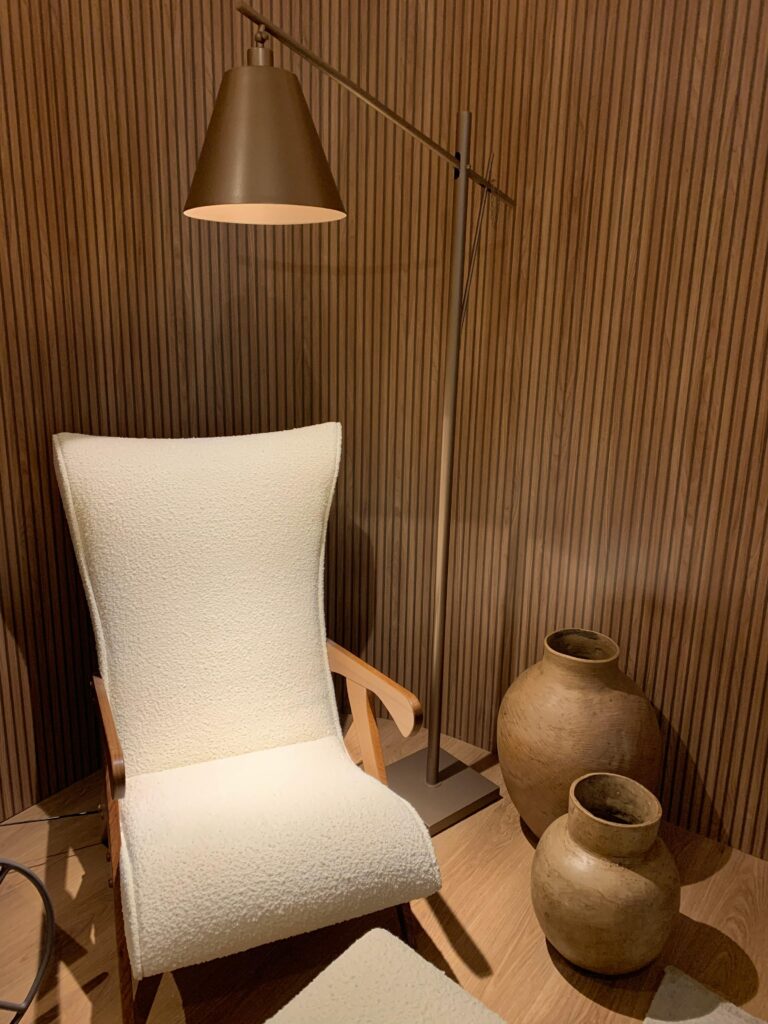 Cadeira clara com iluminária âmbar e vasos de barro decorativos.