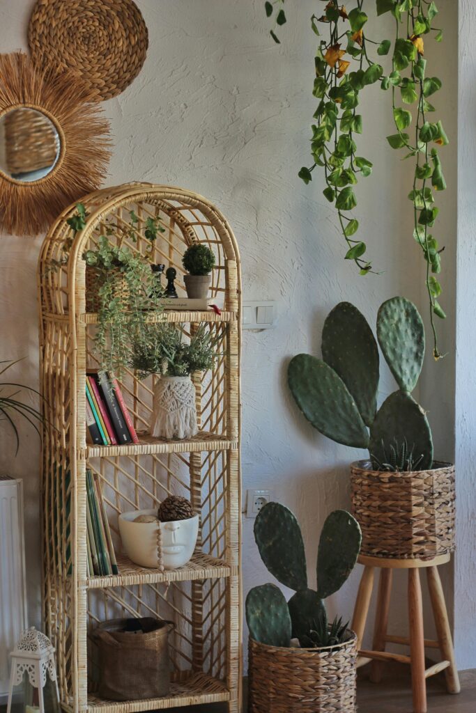 Estante de vime decorada com livros, plantas e cestas em ambiente rústico com cactos e parede de cimento queimado.