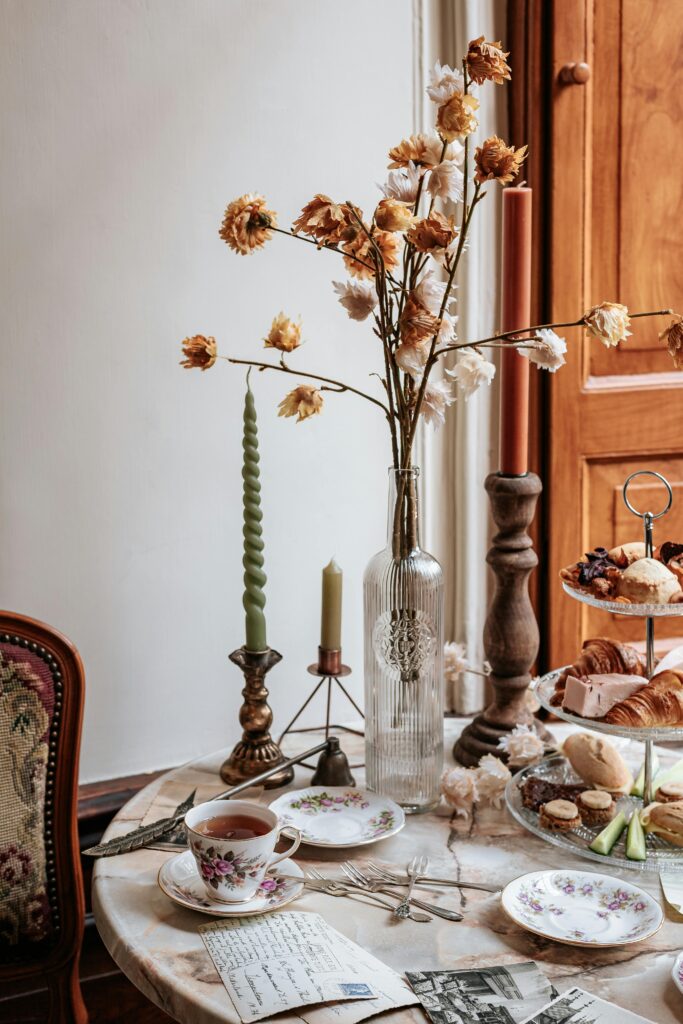 Mesa posta para café da manhã ou chá da tarde, decorada com três diferentes castiçais e velas compridas simples e coloridas.