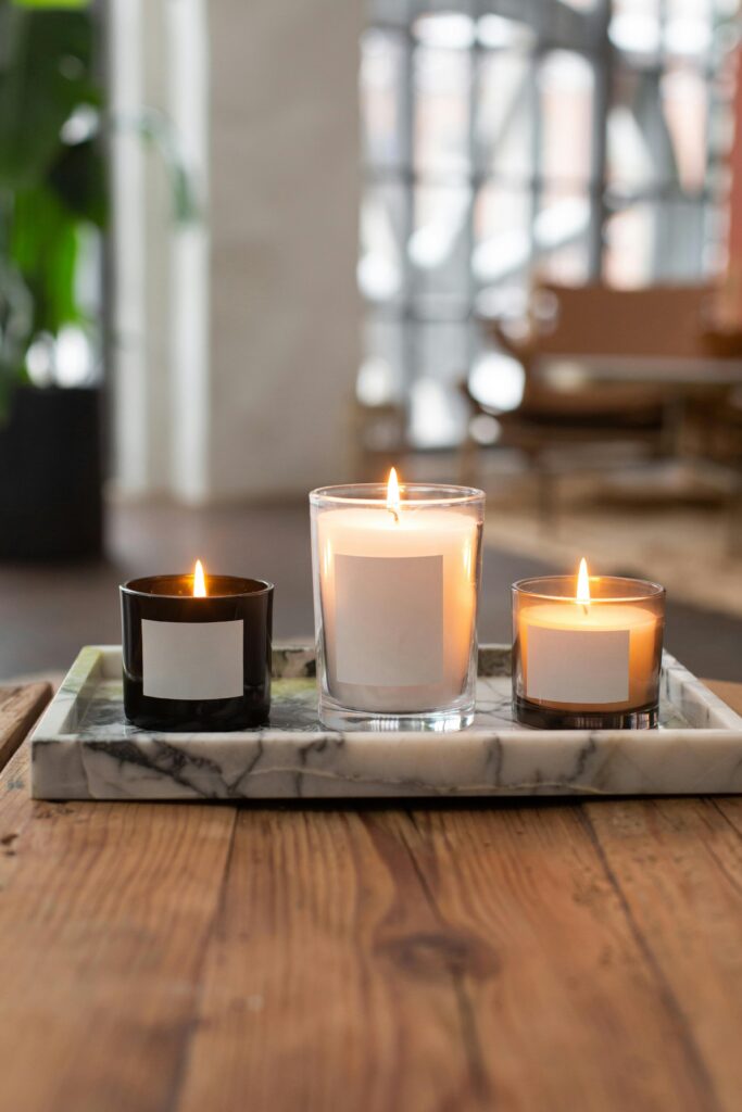 Decoração elegante e simples com velas em potes de vidro, sobre uma bandeja de mármore.