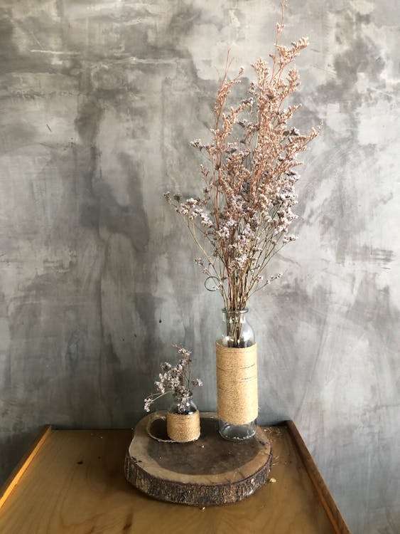 Decoração arranjo com galhos secos. Arranjo rústico com vasos de vidro envoltos em juta sobre base de tronco de madeira.

