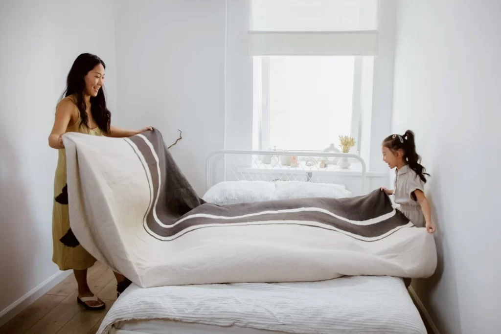 Mãe e filha arrumando a cama, como um dos 7 hábitos simples para manter a casa organizada.