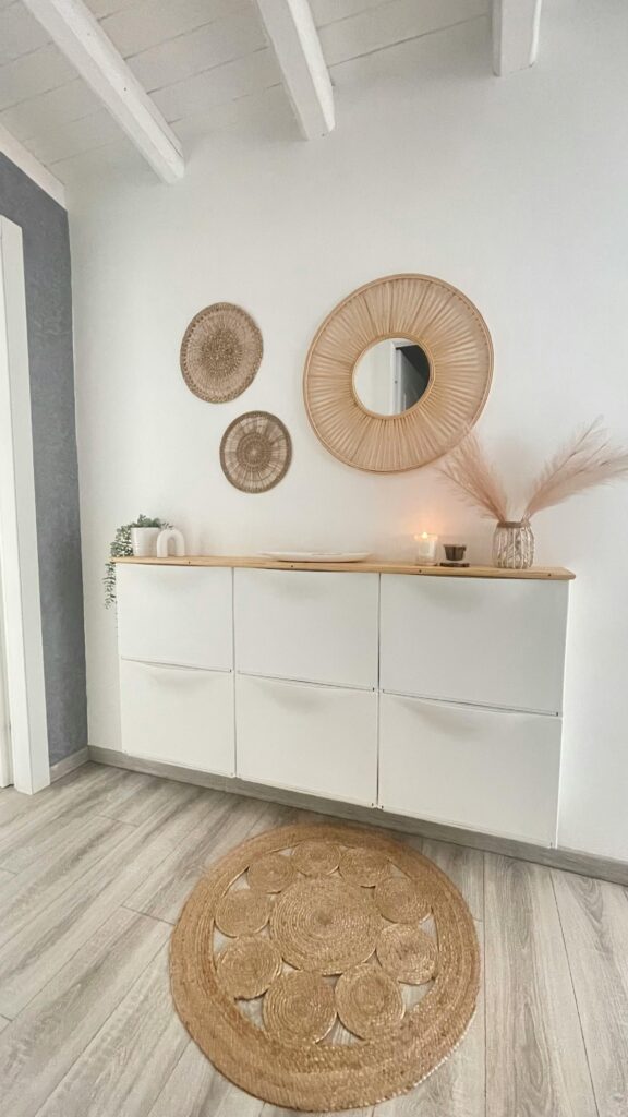 Aparador branco com objetos no estilo boho na decoração. Espelho e mandalas em palha