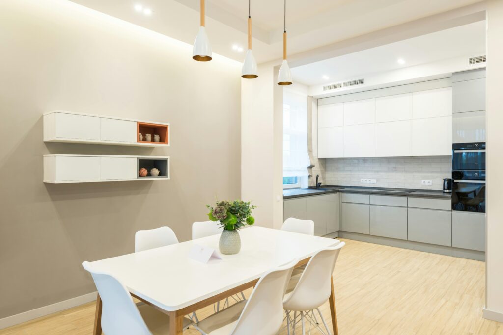 Cozinha e sala de jantar no estilo escandinavo na decoração, com móveis brancos, piso de madeira clara, iluminação pendente e design minimalista.