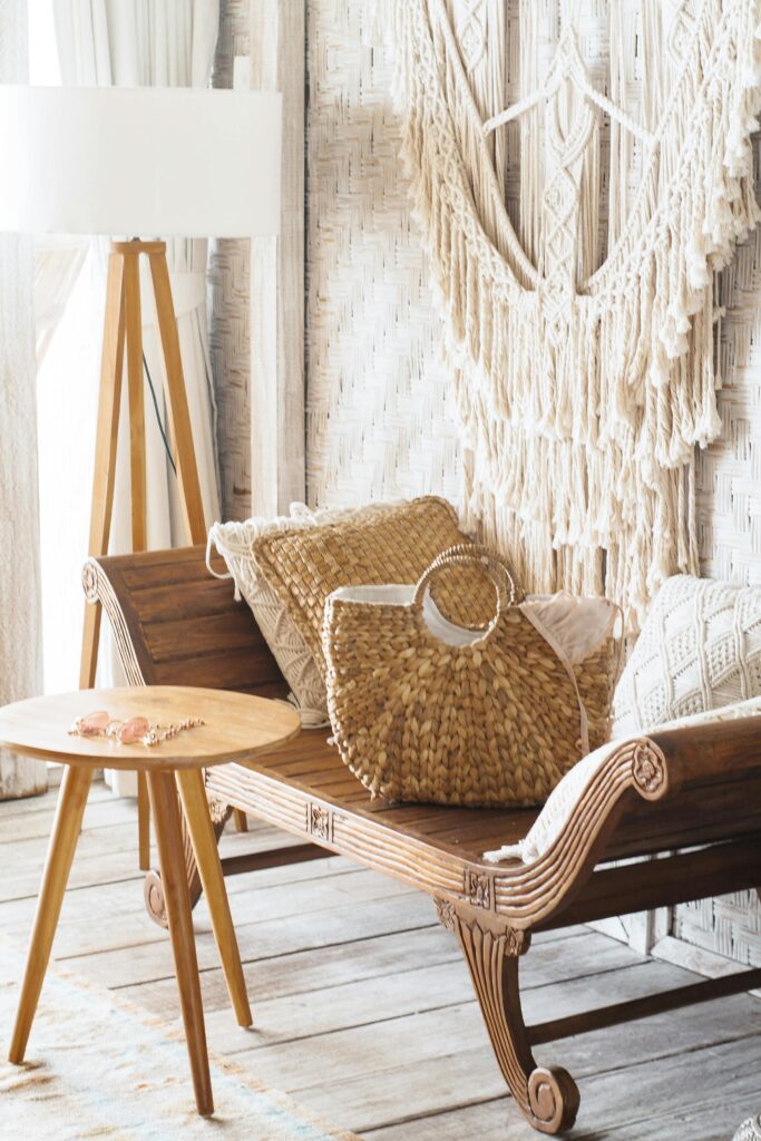 Cantinho com estilo boho na decoração: macramê na parede, almofadas em linha e palha, abajur de chão com cúpula branca larga.