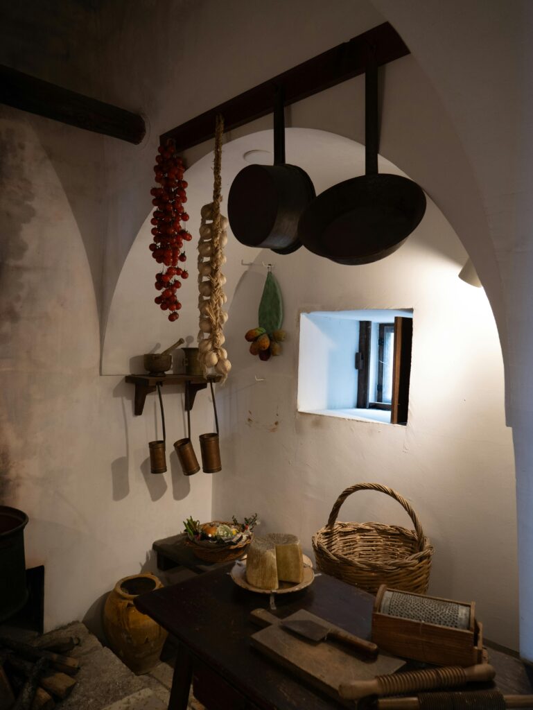 Cozinha rústica com panelas de ferro, mesa de madeira e cestos, destacando o estilo rústico na decoração.