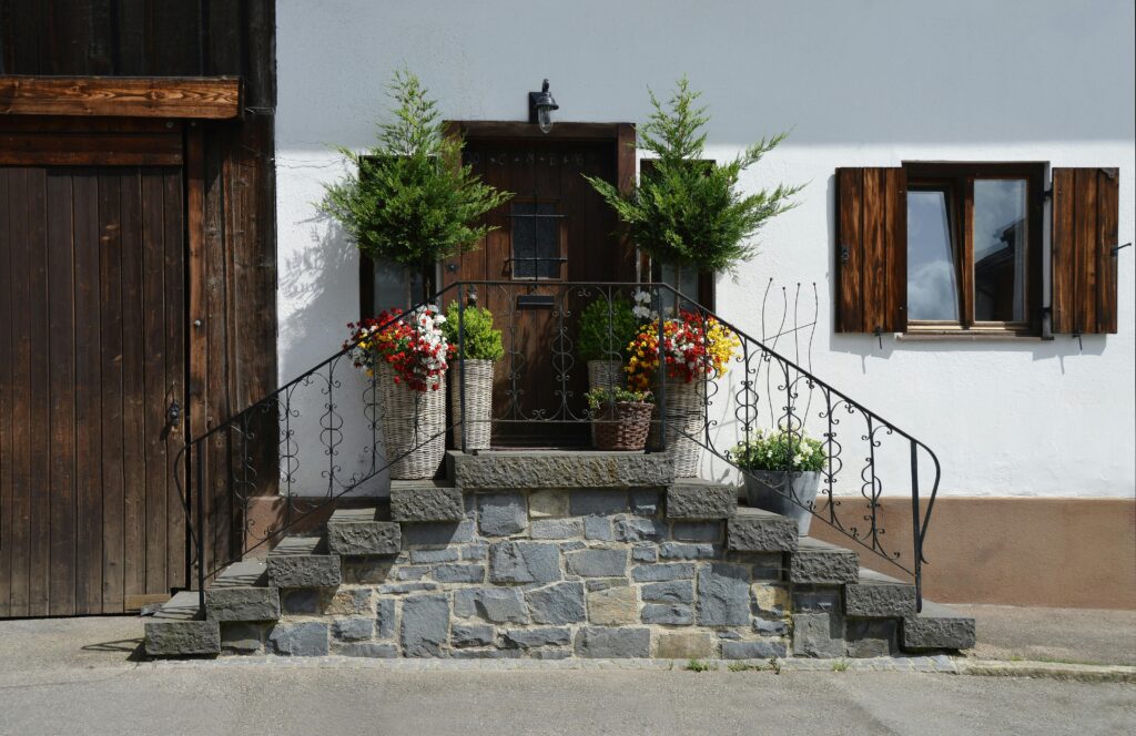 Fachada com porta de madeira, janelas rústicas e degraus de pedra no estilo rústico na decoração.