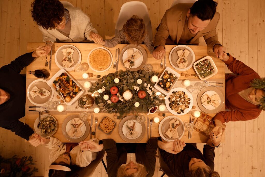União no lar: família reunida em torno da mesa de refeição, com as mãos dadas agradecendo pelo alimento que Deus nos dá. 