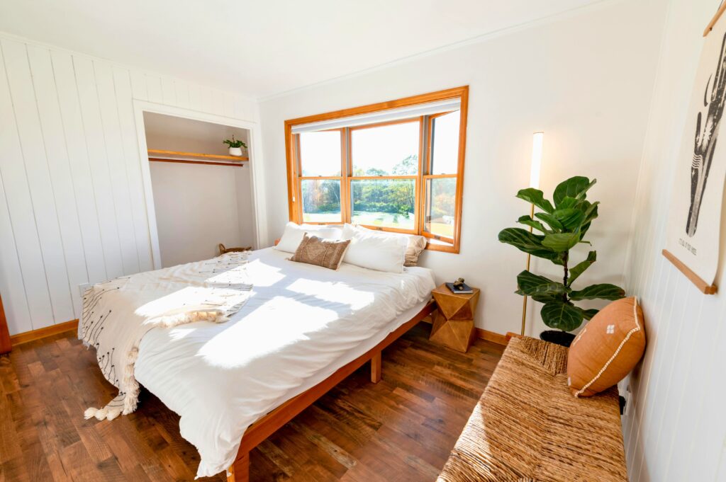 Quarto pequeno organizado com luz natural, móveis em madeira clara e decoração acolhedora