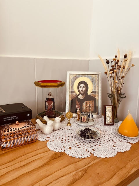 Cantinho da oração em casa com ícone de Cristo, relíquias e terço sobre forro de crochê
