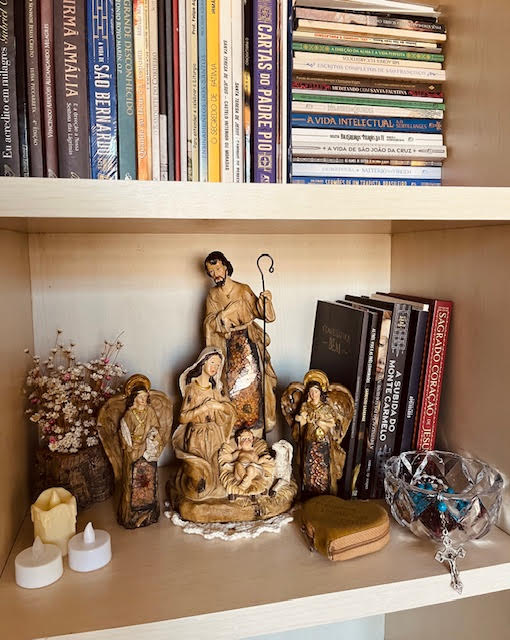 Cantinho da oração em casa integrado à estante com presépio e livros espirituais