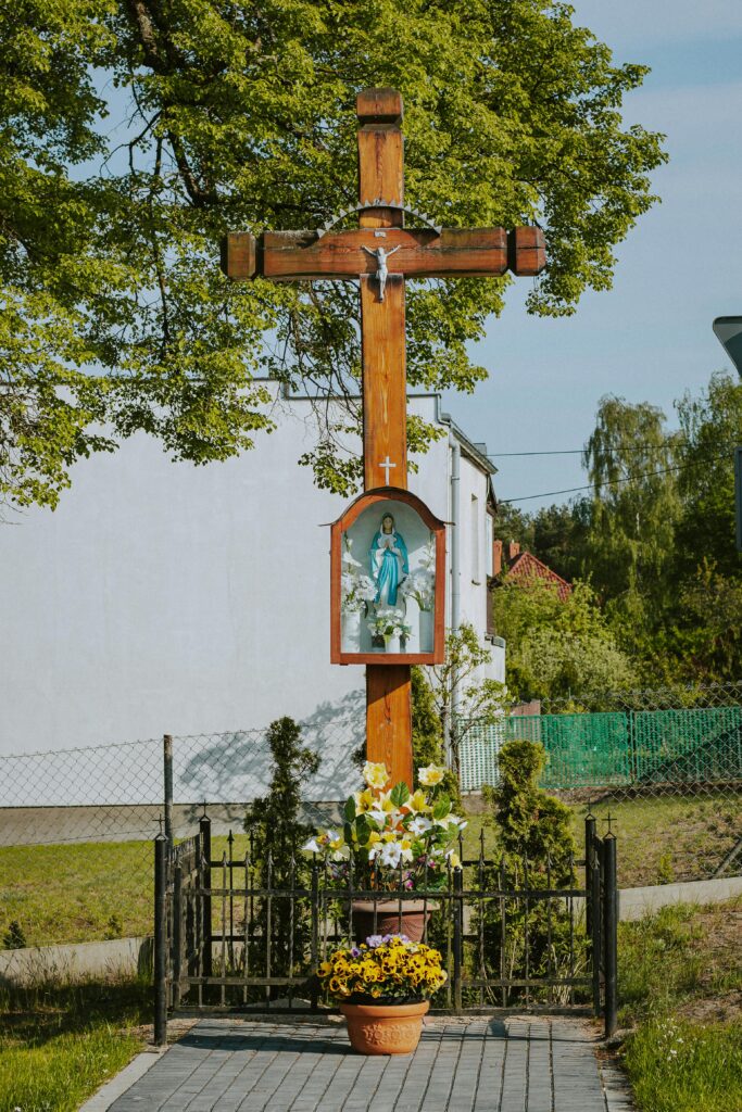 Cantinho da oração em casa com grande cruz de madeira, imagem de Nossa Senhora e flores ao ar livre
