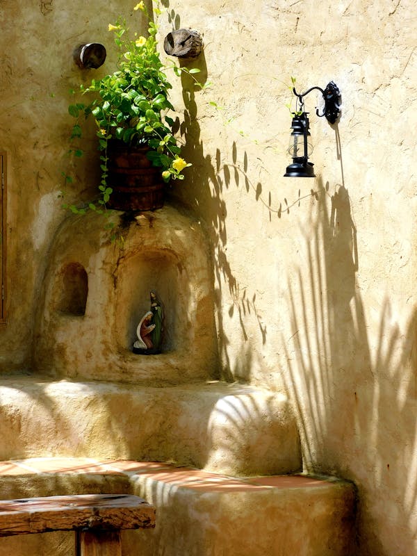 Cantinho da oração no jardim  com nicho na parede, imagem religiosa e vaso verde