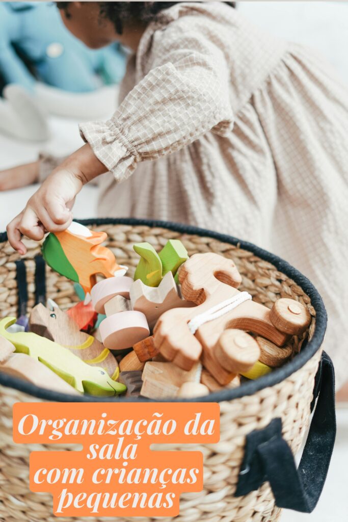 Organização da sala com crianças pequenas usando cestos grandes para guardar brinquedos de madeira.