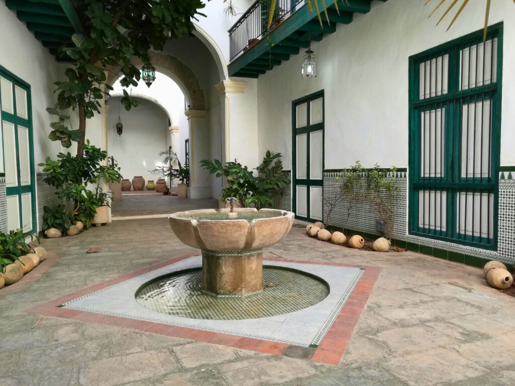 Fonte de água decorativa em pátio interno com estilo clássico e plantas ao redor