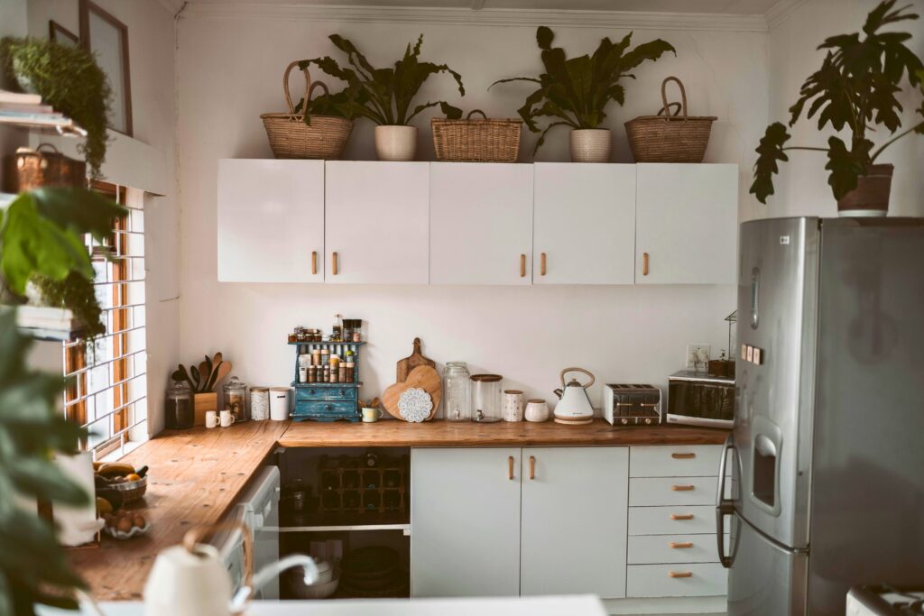 Organização da cozinha pequena com bancadas de madeira, armários brancos e cestos decorativos.