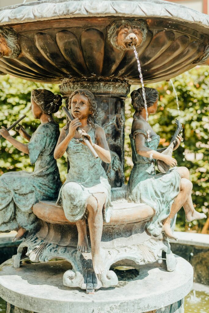 Fonte de água decorativa com esculturas de mulheres em estilo clássico tocando instrumentos