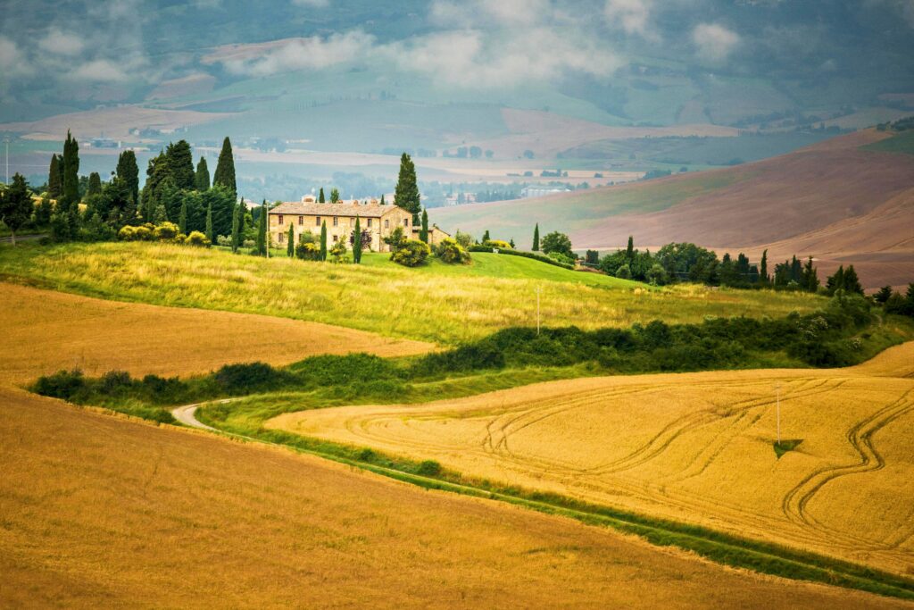 Paisagem tranquila da Toscana com campos dourados e ciprestes, símbolo do ritmo sereno da dolce vita italiana.