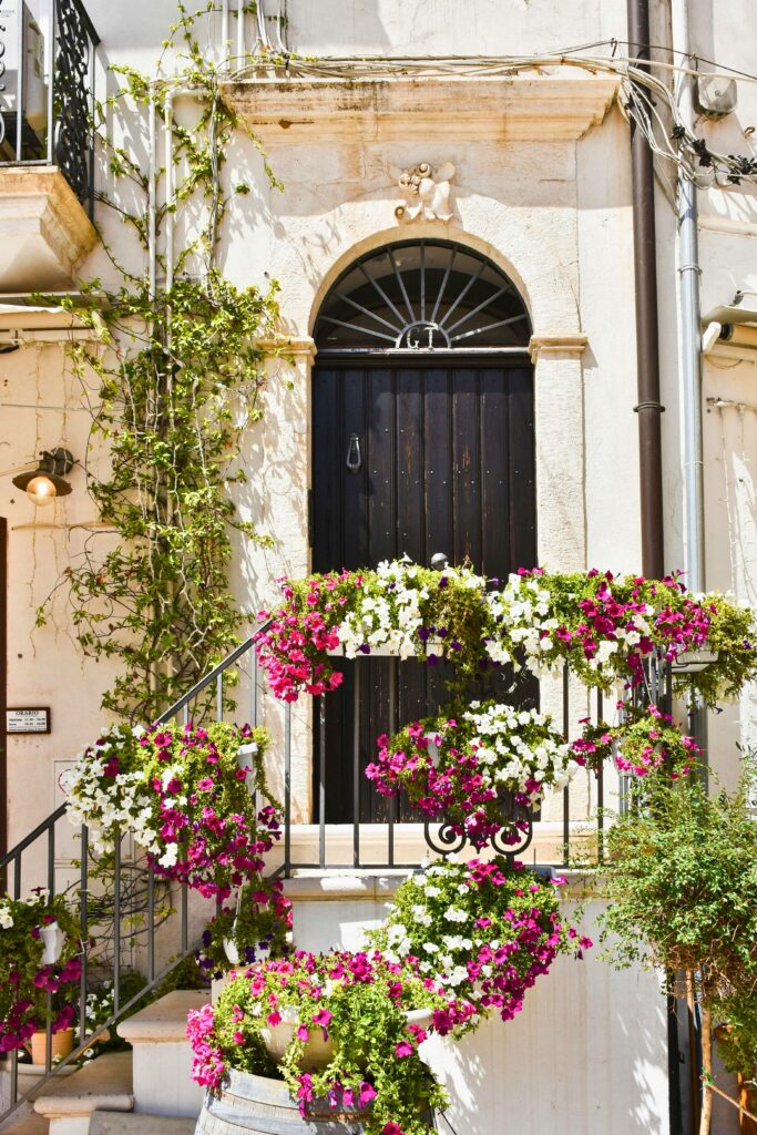 entrada de casa italiana com porta antiga, trepadeiras e flores coloridas no estilo mediterrâneo
