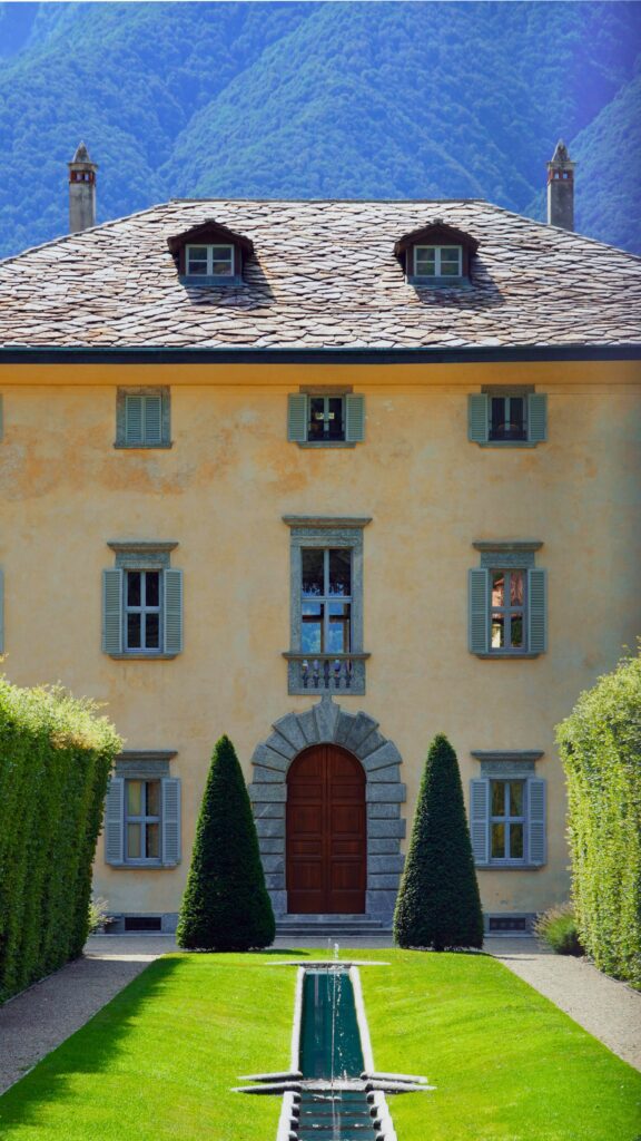 entrada de casa italiana em estilo clássico, com porta em arco e jardim simétrico