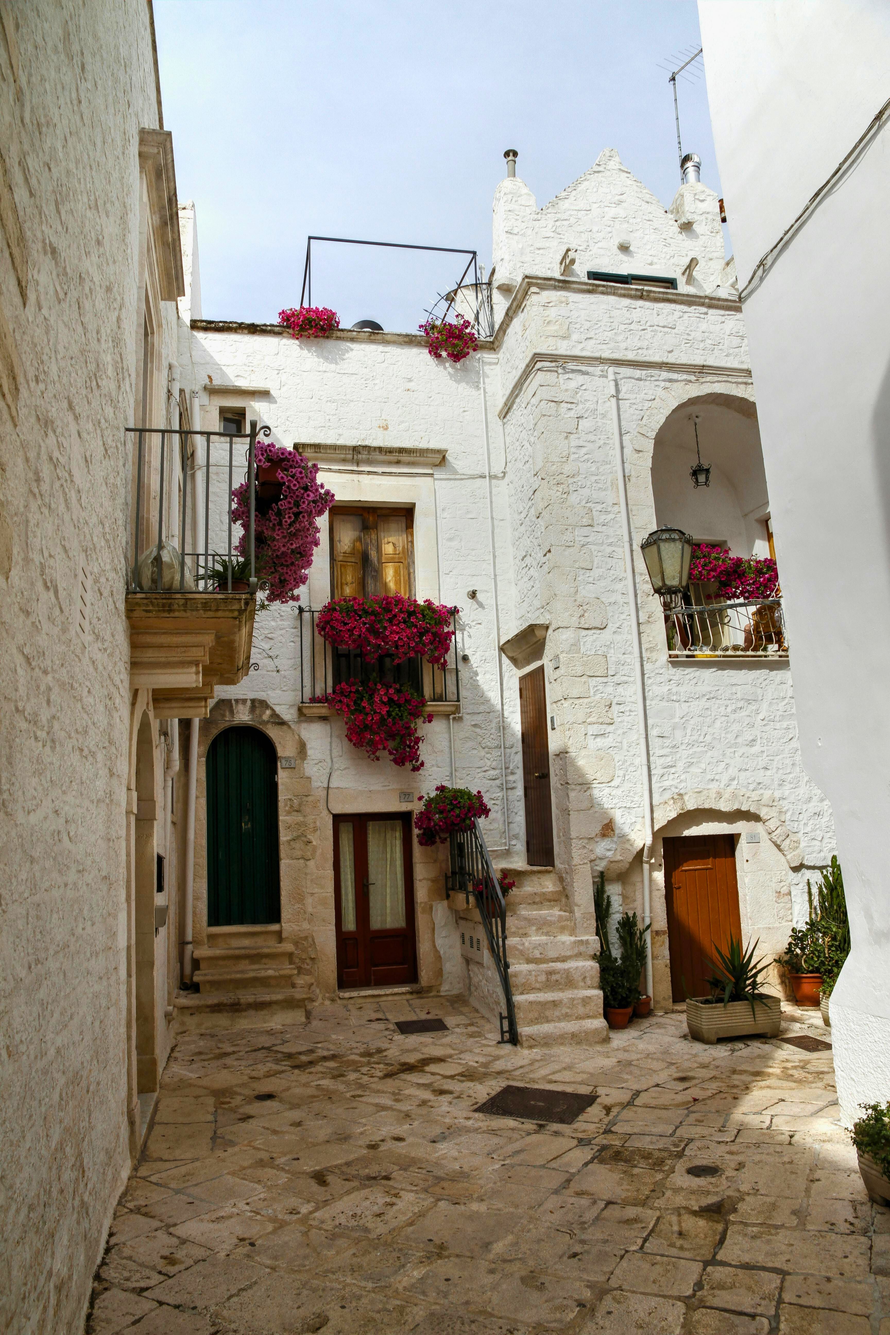 entradas de casas italianas com fachadas brancas, flores pendentes e varandas mediterrâneas
