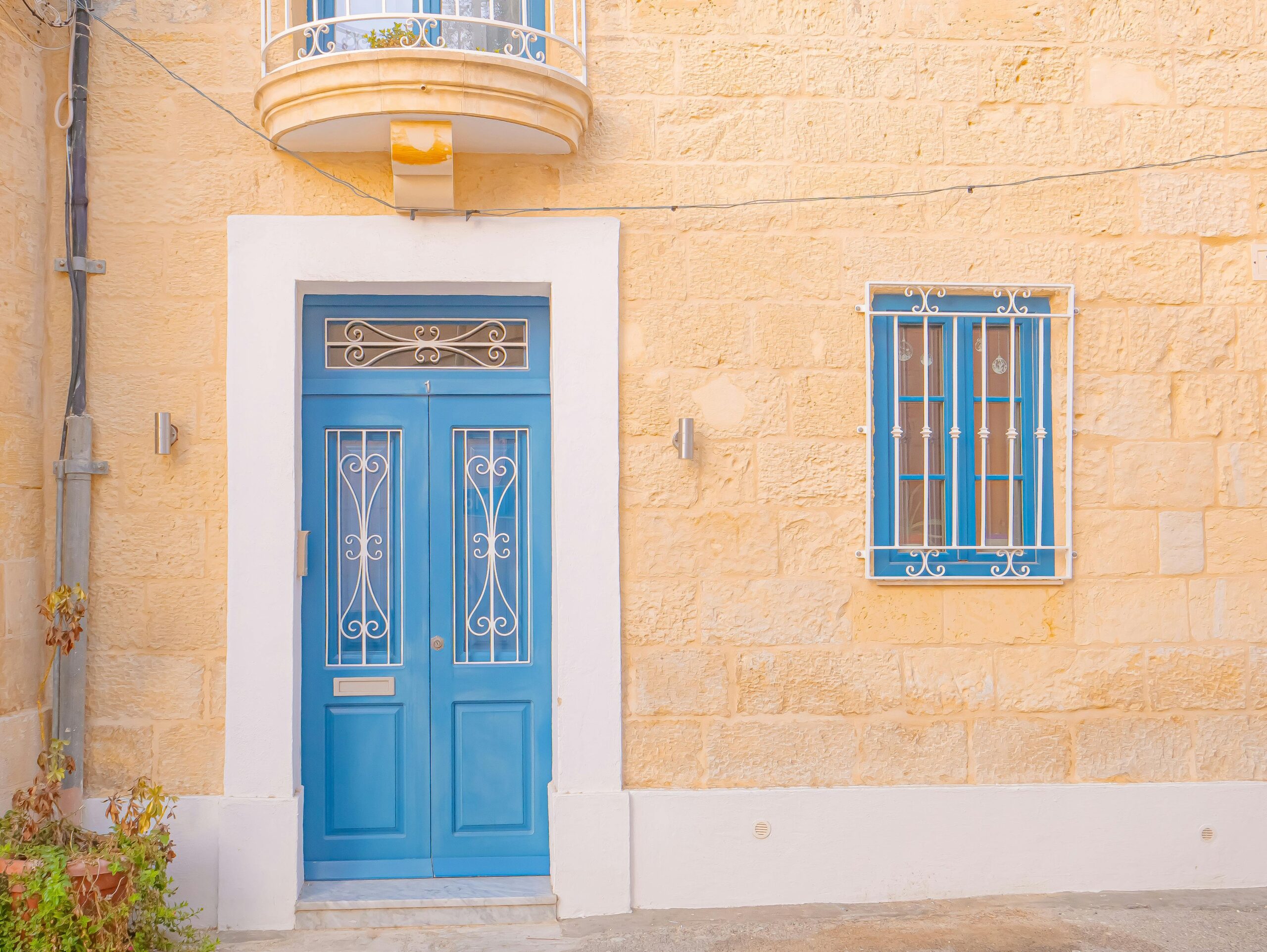 porta azul com moldura branca em fachada amarela suave