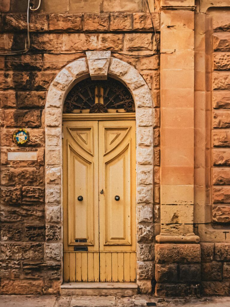 porta bege com arco de pedra em fachada rústica