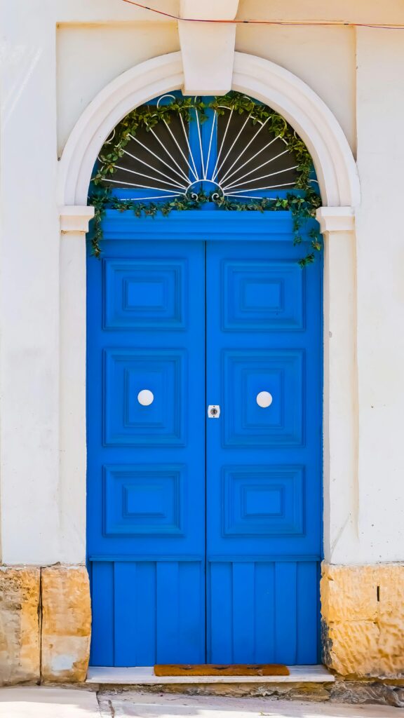 porta azul vibrante com arco branco e detalhe em trepadeira