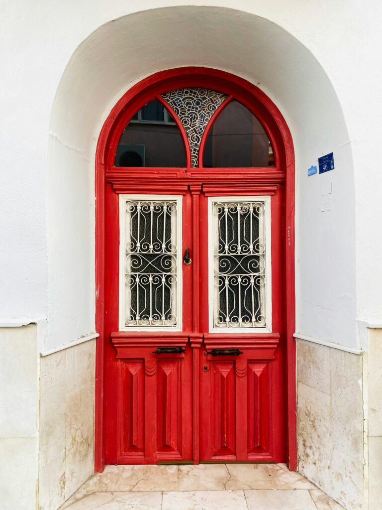 porta vermelha arqueada com detalhes brancos em fachada limpa