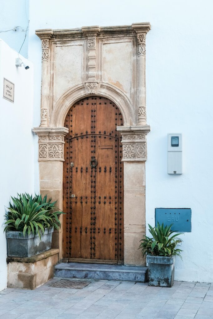 porta de madeira robusta com moldura esculpida e plantas nas laterais