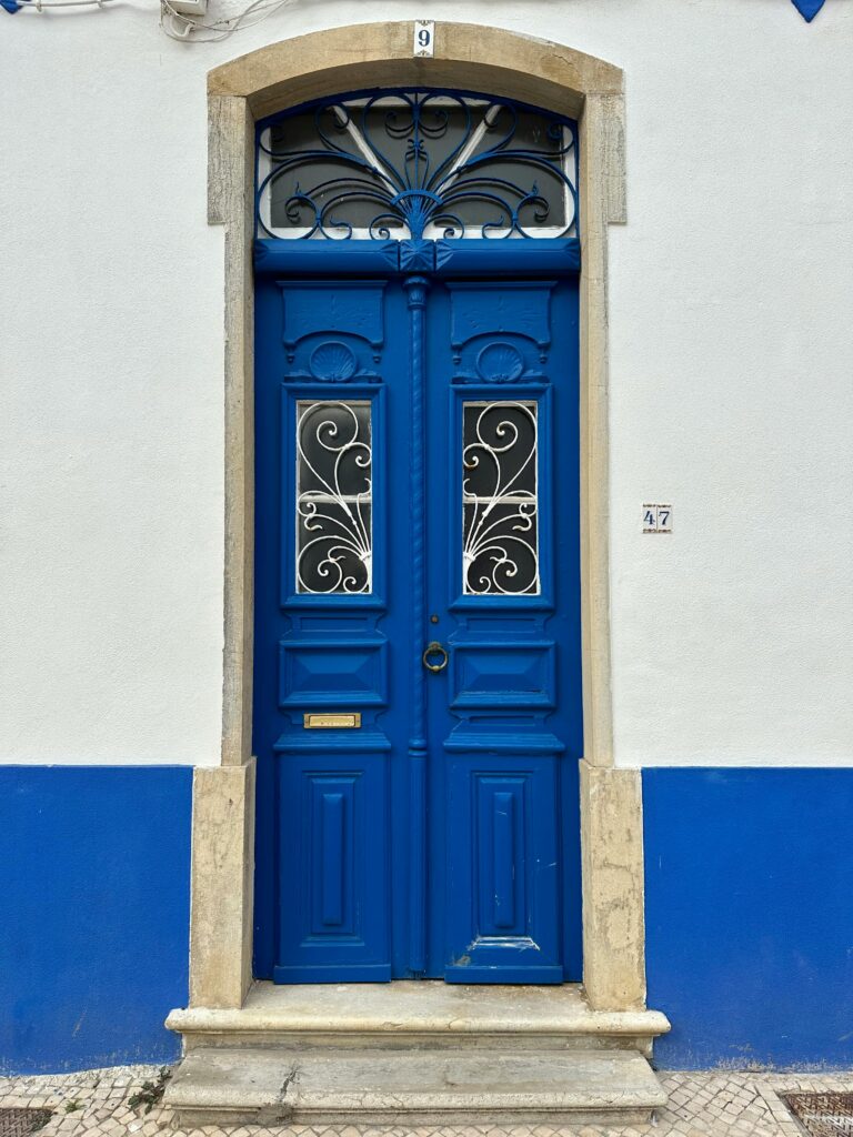 Portas azuis na entrada da casa com moldura em pedra clara e degrau frontal