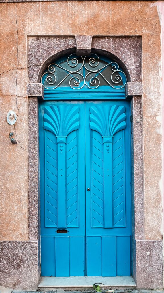 Portas azuis na entrada da casa com arco em pedra e acabamento clássico