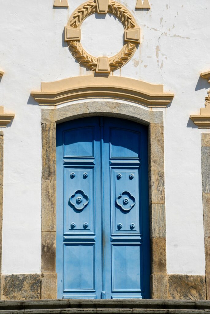 Portas azuis na entrada da casa com estilo clássico e detalhes decorativos